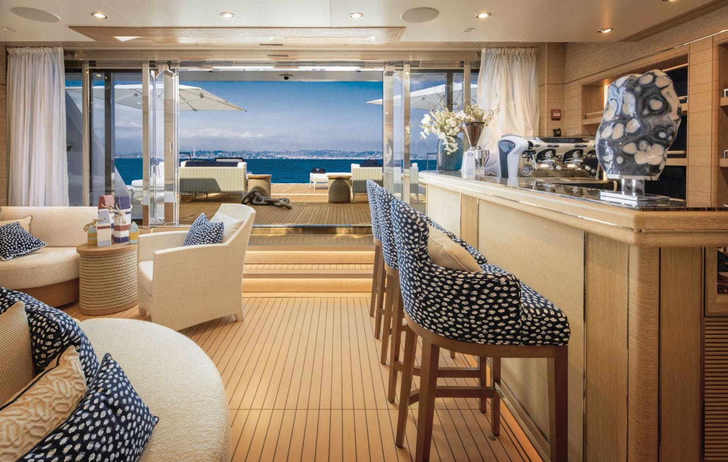 Salon bar and seating area with opened doors looking out to the aft deck. >