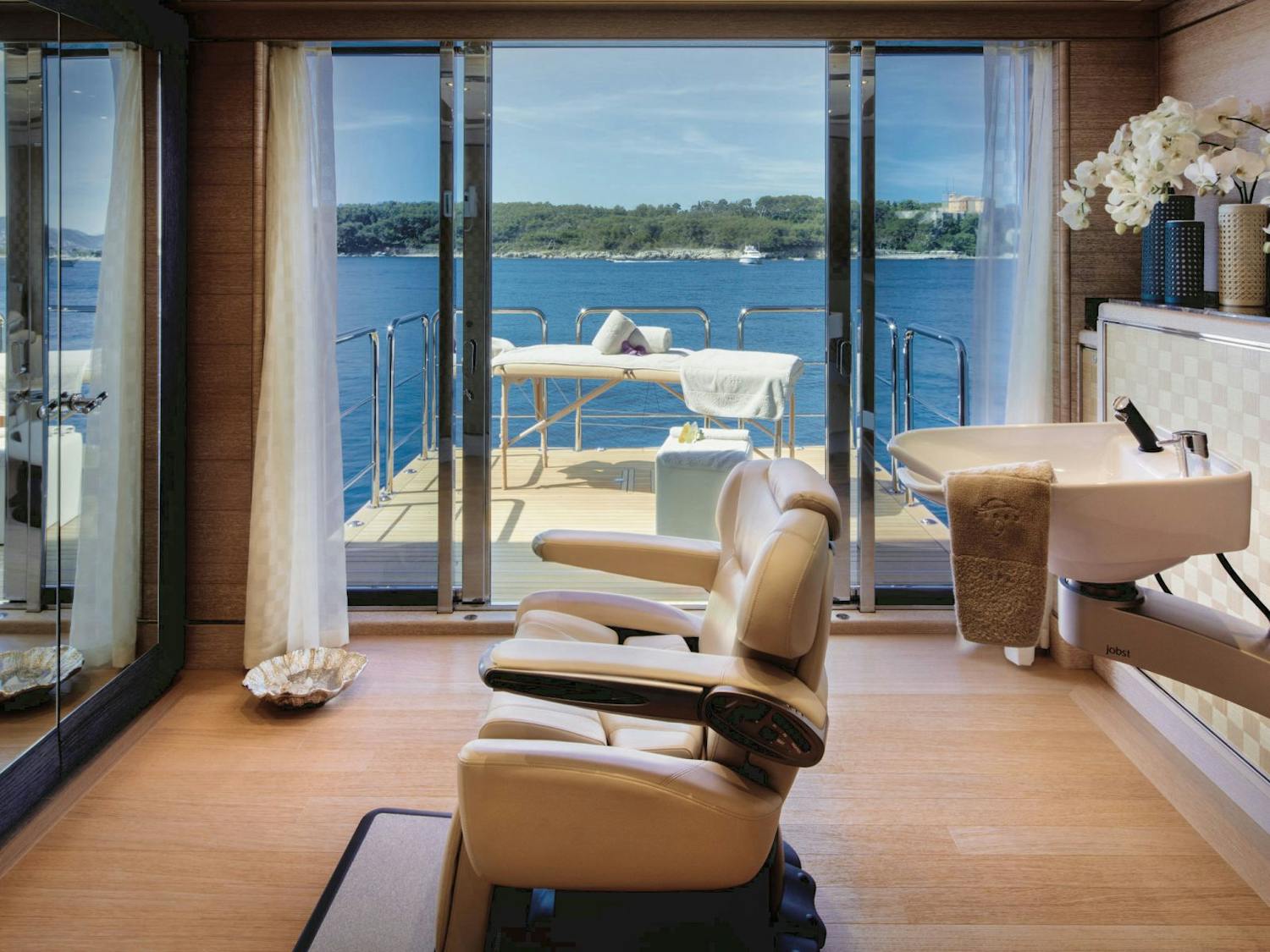 Inetrior spa chair and sink with massage table on the balcony overlooking the water. >