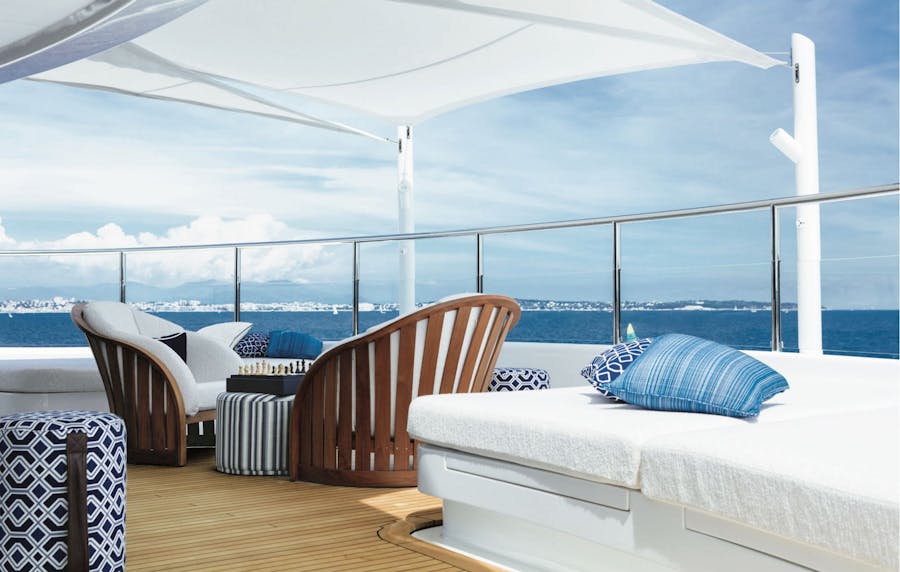 Outdoor furniture on the deck outside of the main cabin covered by a sun shade. >